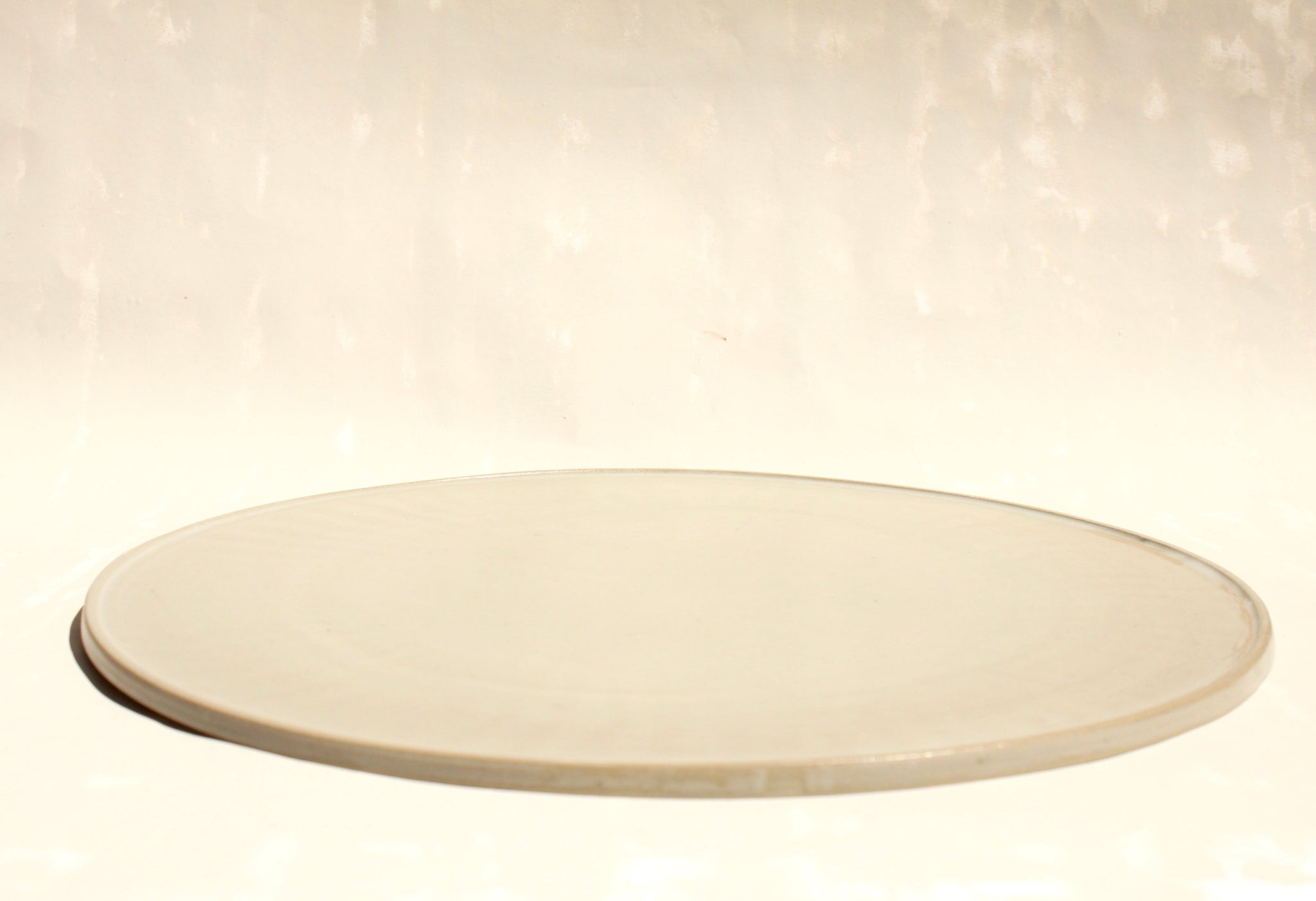 Modularer Pizzateller aus der Kollektion Rosa Morada von Martina Geroni in der Tonfarbe Fiore di Cotone, handgefertigtes Steingutobjekt mit flacher, klarer Form, nutzbar als Teller, Servierplatte oder Platzset.