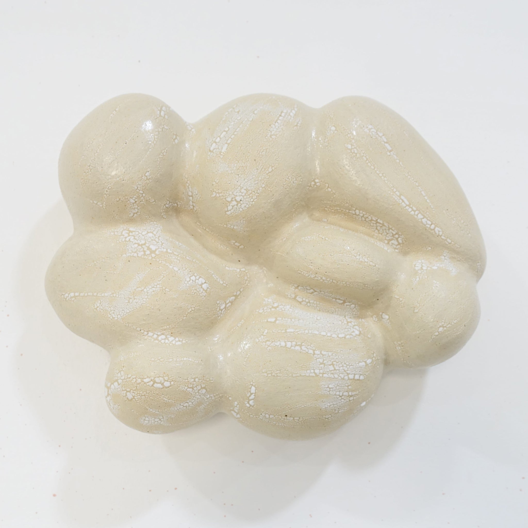 Keramische Wandskulptur in organischer, wolkenartiger Form; helle, leicht cremeweiße Oberfläche mit feinen Rissstrukturen und weicher, gewölbter Modellierung.